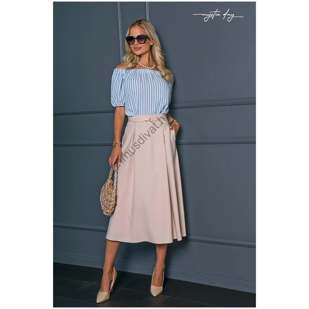 Mystic Day elején rakott, lefelé bővülő bézs midi szoknya, oldalán svéd zsebekkel, anyagábol készült arany színű csatos gumis övvel​, nem rugalmas szövött anyagból, hátulján cipzáras záródással